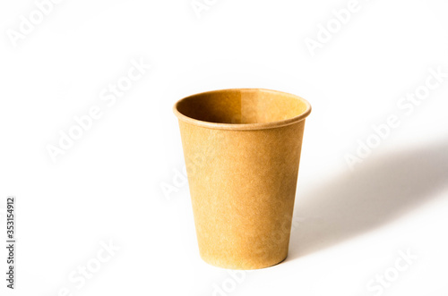 Brown paper cup for coffee, tea, a drink from environmental materials on a white background. One paper cup is on the right and a shadow falls on it on a white background.