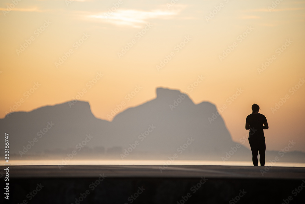 A woman watches the sunrise on the beach.