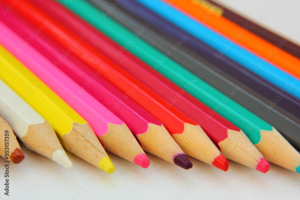 Color pencils lie in a row on white paper. Color pencils lie in a row on white paper.