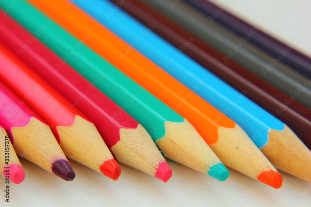 Color pencils lie in a row on white paper. Color pencils lie in a row on white paper.