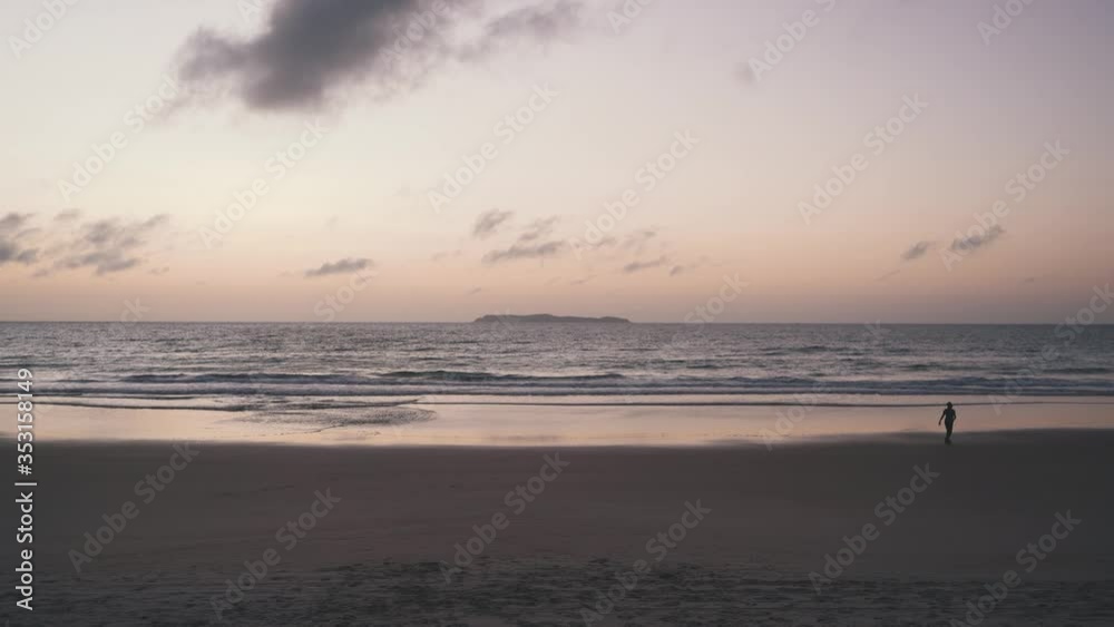Woman alone walking on beach before sunrise Woman alone walking on beach before sunrise
