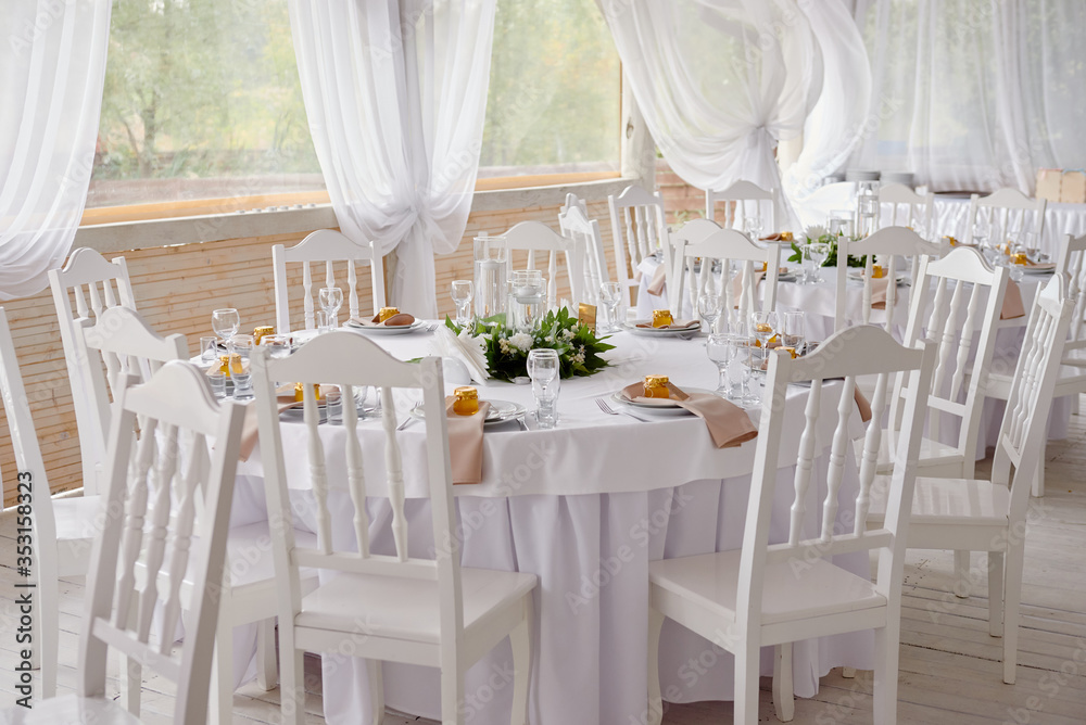 Table setting with blank guest card, plates with napkins and cutlery, copy space. Place setting at wedding reception. Round table served for banquet in restaurant
