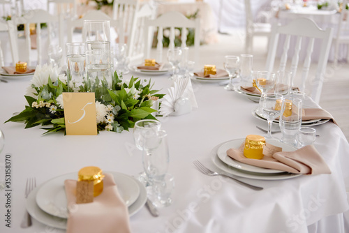 Table setting with blank guest card, plates with napkins and cutlery, copy space. Place setting at wedding reception. Round table served for banquet in restaurant