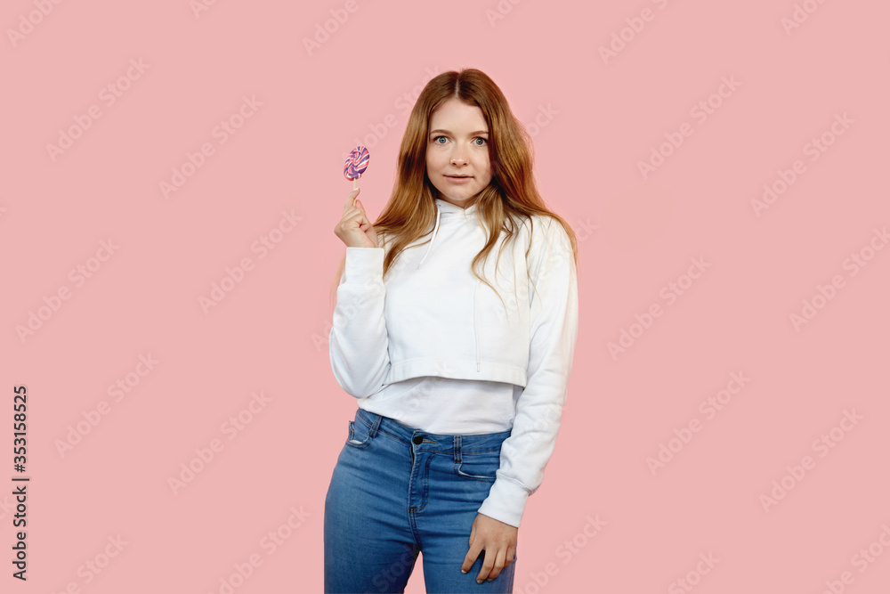 A beautiful young girl with a colorful lollipop on a stick in her hands.