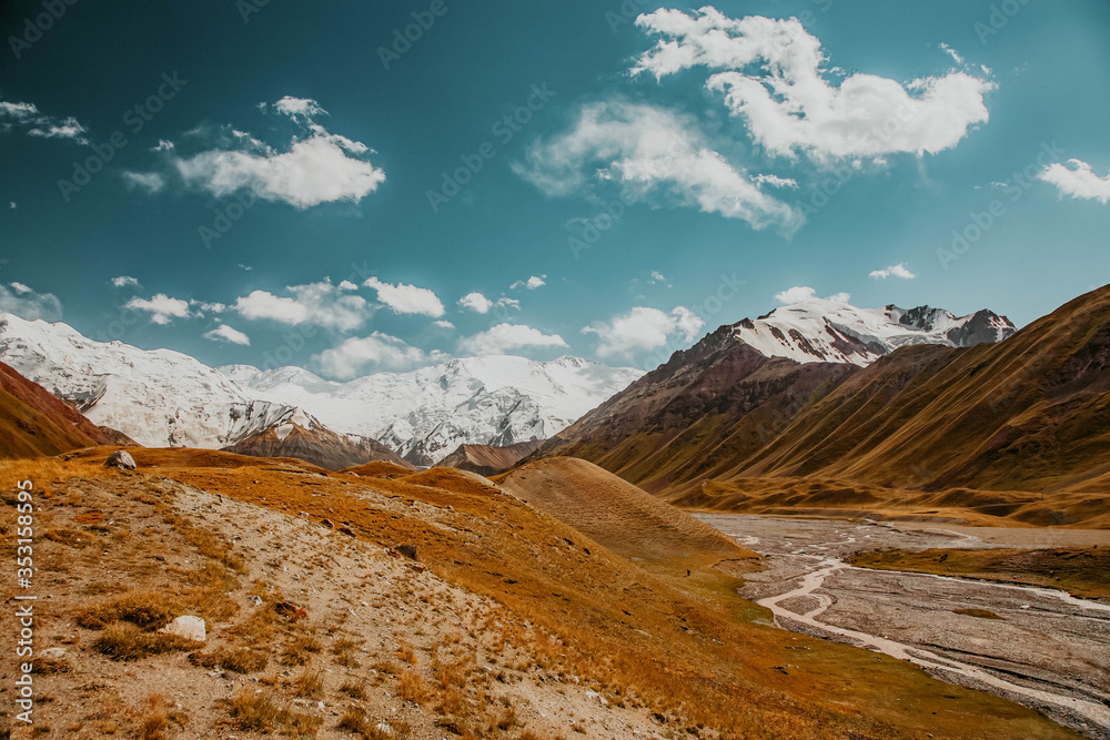 Beautiful mountainious landscape. Snowy mountain peaks. Hilly valley.