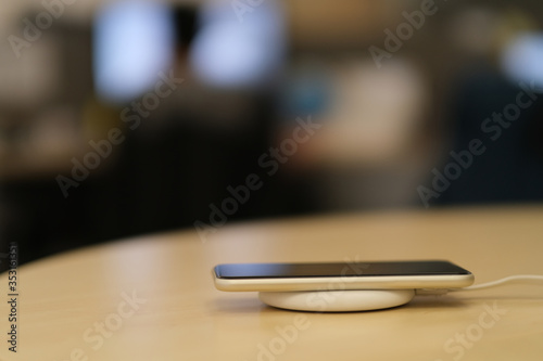 close up one smartphone on wireless charger. blurred office background