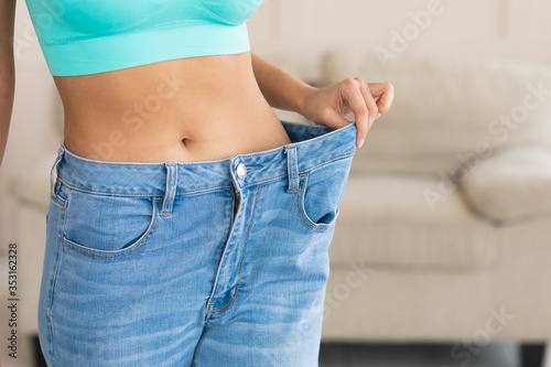 Unrecognizable Woman Wearing Big Jeans After Diet And Slimming Indoor
