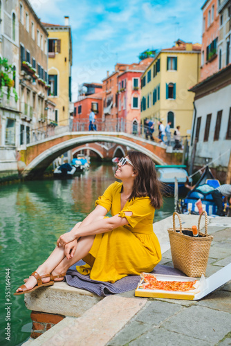 woman sitting on pond with view of venice canal eating pizza