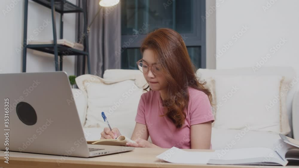 Young Asia teen girl student distance learning lesson with online teacher and study on computer laptop in living room from home at night. Social distancing, quarantine for corona virus prevention. Young Asia teen girl student distance learning lesson with online teacher and study on computer laptop in living room from home at night. Social distancing, quarantine for corona virus prevention.