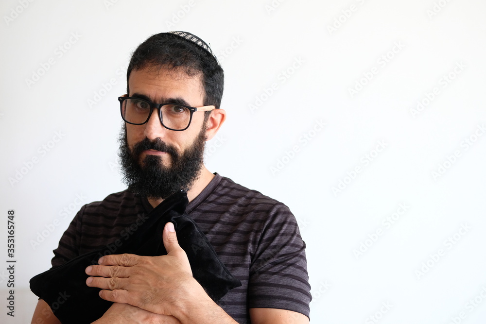 Bearded Jewish holding his Tallit (talis) The man is standing in front of a white background and has the Tallit bag in he's chest Bearded Jewish holding his Tallit (talis) The man is standing in front of a white background and has the Tallit bag in he's chest