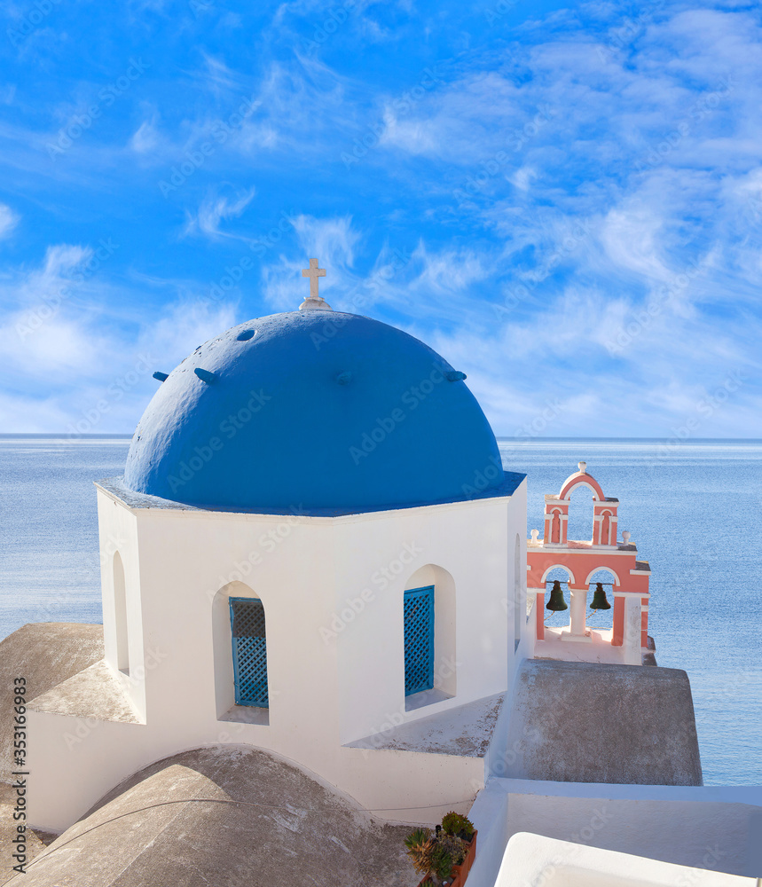 Blue Domed Anastasi Greek church and belfry against volcano caldera in Oia town on Santorini island, Cyclades, Greece