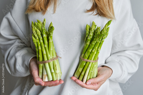 Green asparagus in the hands of a girl. Bunch of ripe fresh asparagus. Healthy organic food. Cooking in home. Natural vitamins  raw ingredient for eating. Handpicked bio asparagus