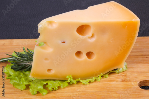 Maasdam cheese in the board served salad leaves