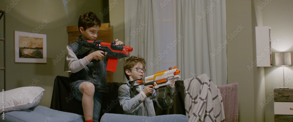 Kids having a toy gunfight with their father at home. Family having fun ...