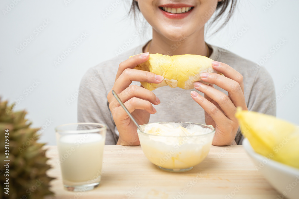 Closeup hand holding durian on table wooden. Woman holding prepare topping durian fruit for eating with ice scream and milk. Focus hand with durian. Closeup hand holding durian on table wooden. Woman holding prepare topping durian fruit for eating with ice scream and milk. Focus hand with durian.