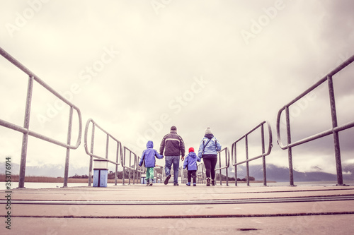 Family On Winter Vacation Walking Across A Bridge Holding Hands