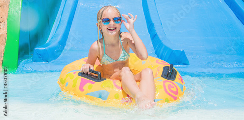 Child on water slide at aquapark. Summer holiday.