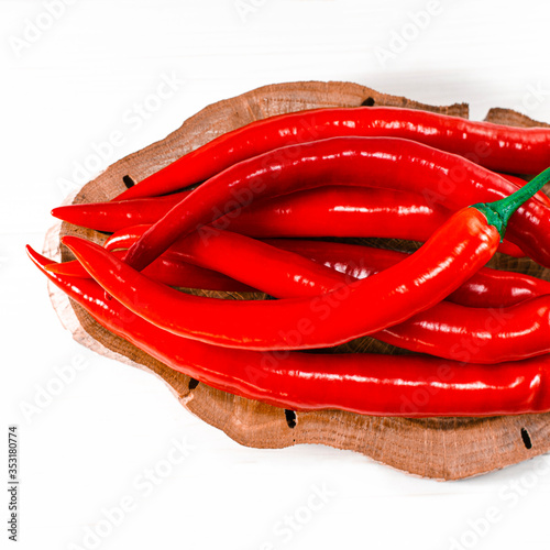 Sharp red chilli perzi lie on a cutting board on a white wooden table photo