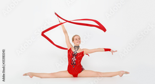 Obraz na plátně Professional gymnast with red ribbon doing leg split on white background, panora