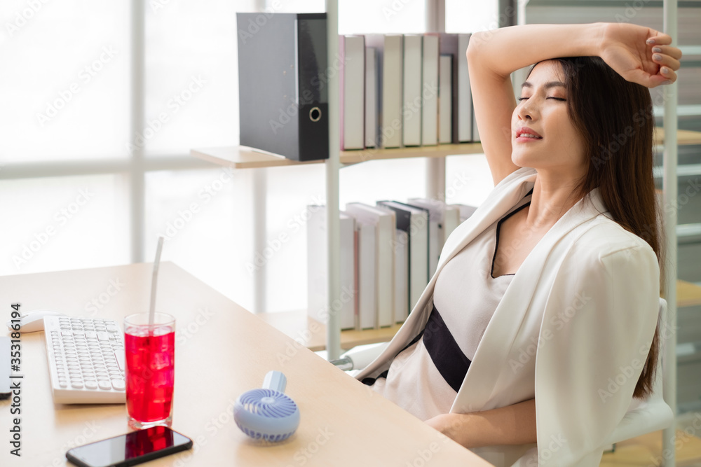 Asian woman suffers from heat while working in the office with cold water Asian woman suffers from heat while working in the office with cold water