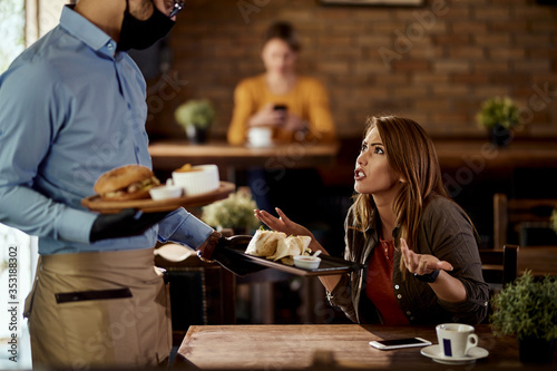 Displeased customer arguing with waiter about food he served to her in a pub.