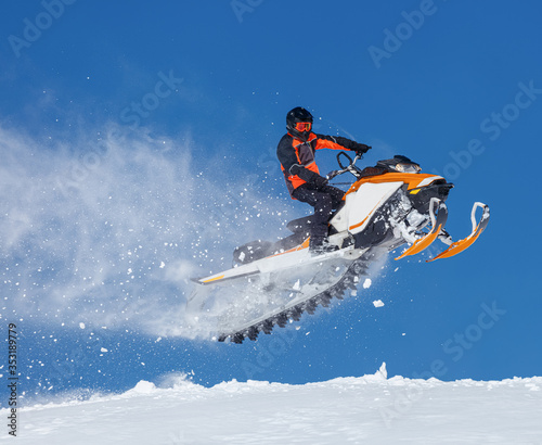 snowmobile rider jumping through snow. RIDER MAN WITH HELMET JUMPING WITH SNOWMOBILE BETWEEN SKY ON WINTER. a bright suit and a snow motorcycle. Extreme winter sport. high resolution and photo quality
