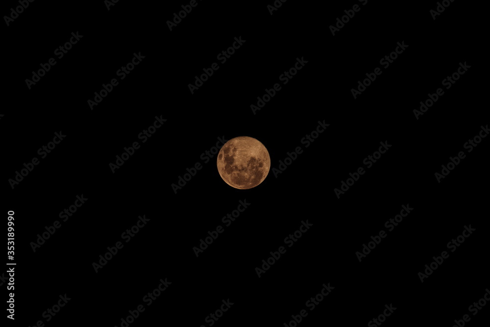 Full moon with reddish tones, floating isolated at night in the southern hemisphere.