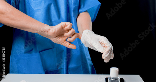 Mani di una dottoressa donna mentre si mette i guanti photo