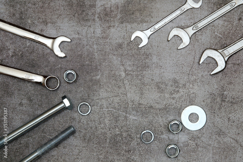 ring spanners and ordinary wrench, bolt nut and washers on a gray concrete background. top view.