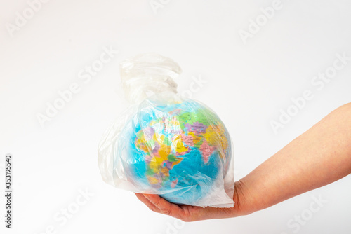  Image of human hand holds the planet earth in a white plastic bag over white background