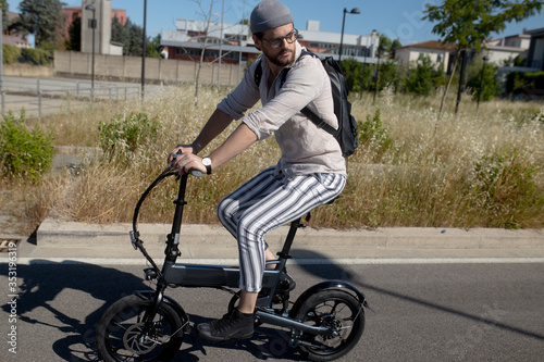 Caucasian attractive man rides his e - bike on the street to go to work and in his leisure. Electric bibycle concept. Ecologic mobility concept. Modern transportation. Electric biking . Cycling man 
