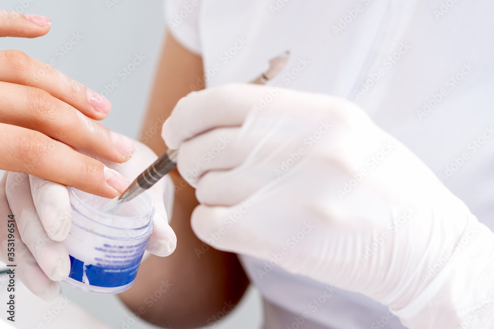 Manicure master hands are covering clear varnish to female nail. Care nail fingers of hands.