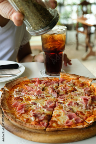 close-up ham pizza , sprinkle oregano,with a glass of cola.background