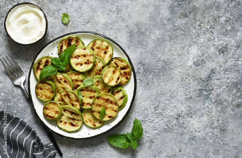 Grilled zucchini with sauce on concrete background. View from above. Grilled zucchini with sauce on concrete background. View from above.