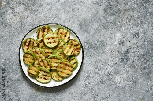 Grilled zucchini with sauce on concrete background. View from above.