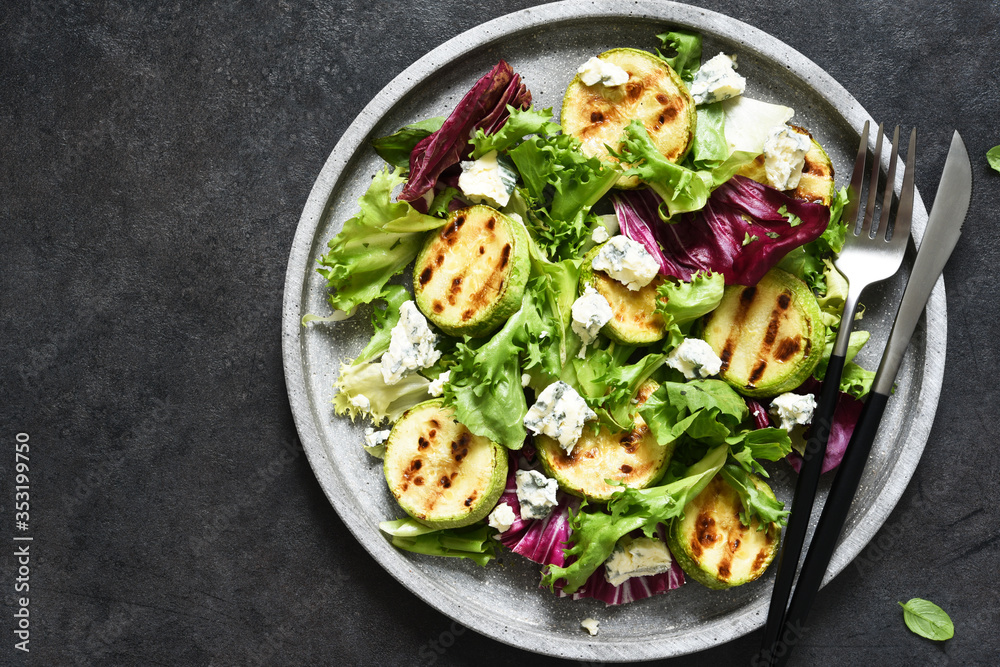 Mix salad with grilled zucchini and sauce on a black background.Top view with copy space. Mix salad with grilled zucchini and sauce on a black background.Top view with copy space.