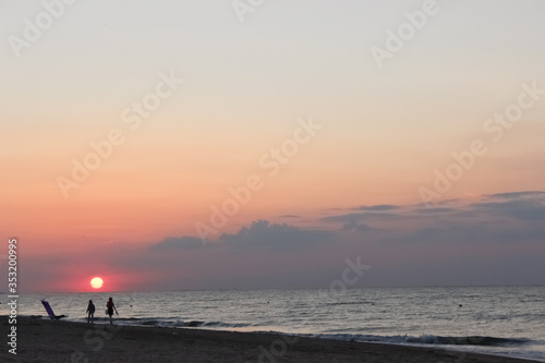  Beautiful sunset on shore of the Sea of       Azov. Pink sun hiding behind the horizon  orange sky and clouds