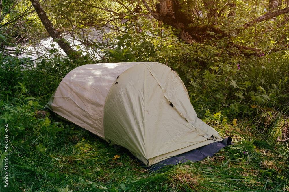 Single tent on the bank of mountain river