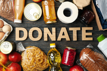 Different food and text Donate on wooden background, top view. Donation concept