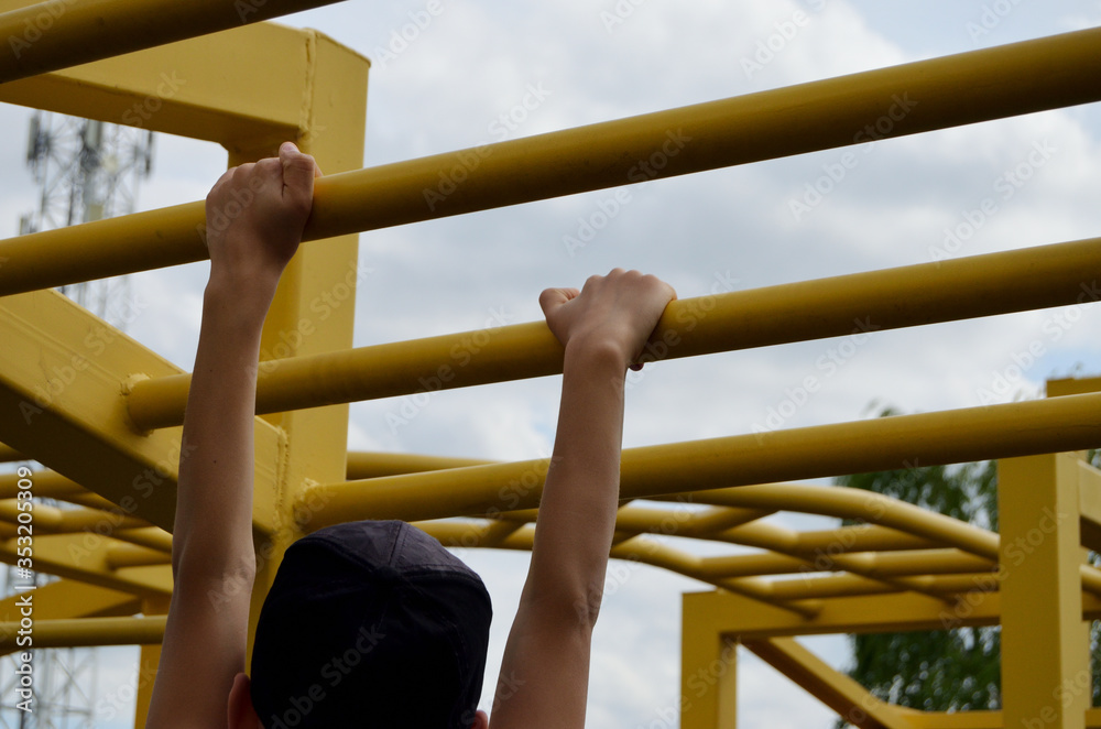Boy in his arms moves on a yellow turnstile in an open-air park Boy in his arms moves on a yellow turnstile in an open-air park