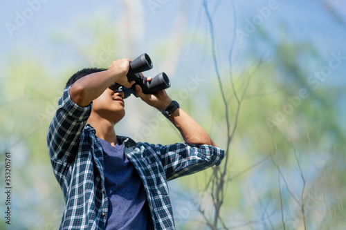 Close-up of Asian handsome man holding / looking / watching using binoculars with copyspace