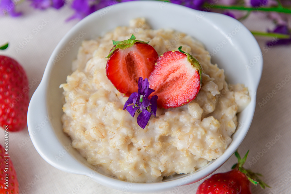 Oatmeal with strawberries in a white plate with a spoon. Lunch. Healthy food. Healthy lifestyle. Close-up Oatmeal with strawberries in a white plate with a spoon. Lunch. Healthy food. Healthy lifestyle. Close-up