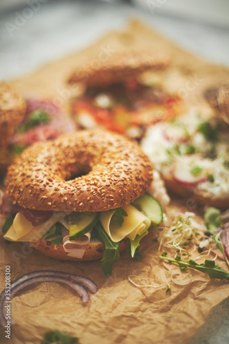 Bagel sandwiches with various toppings, salmon, cottage cheese, hummus, ham, radish and fresh herbs
