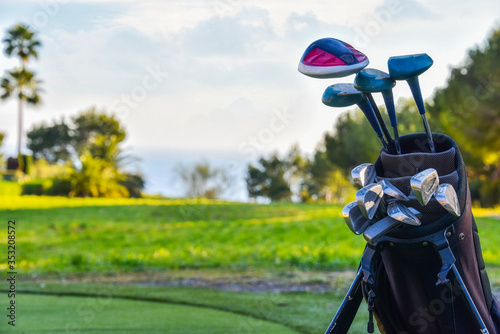 Golf clubs drivers over green field background
