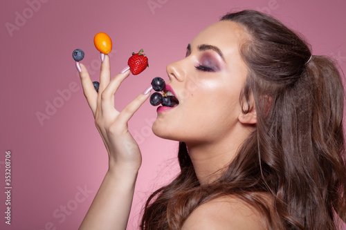 Young sexy woman eating fruits from her fingers