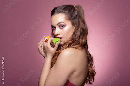 Young sexy woman eating color macarons candies