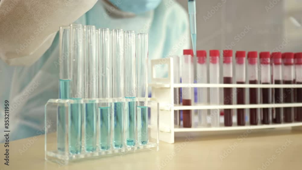 Blood test in the laboratory. Lab technician in protective clothing working with the dispenser. Blood test in the laboratory. Lab technician in protective clothing working with the dispenser.