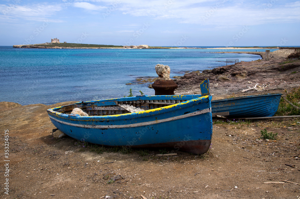 Italy Sicily , Portopalo di Capopassero (SR), 03 May 2019: Boat typical of local fishermen and in the background the Island of Capopassero. Italy Sicily , Portopalo di Capopassero (SR), 03 May 2019: Boat typical of local fishermen and in the background the Island of Capopassero.