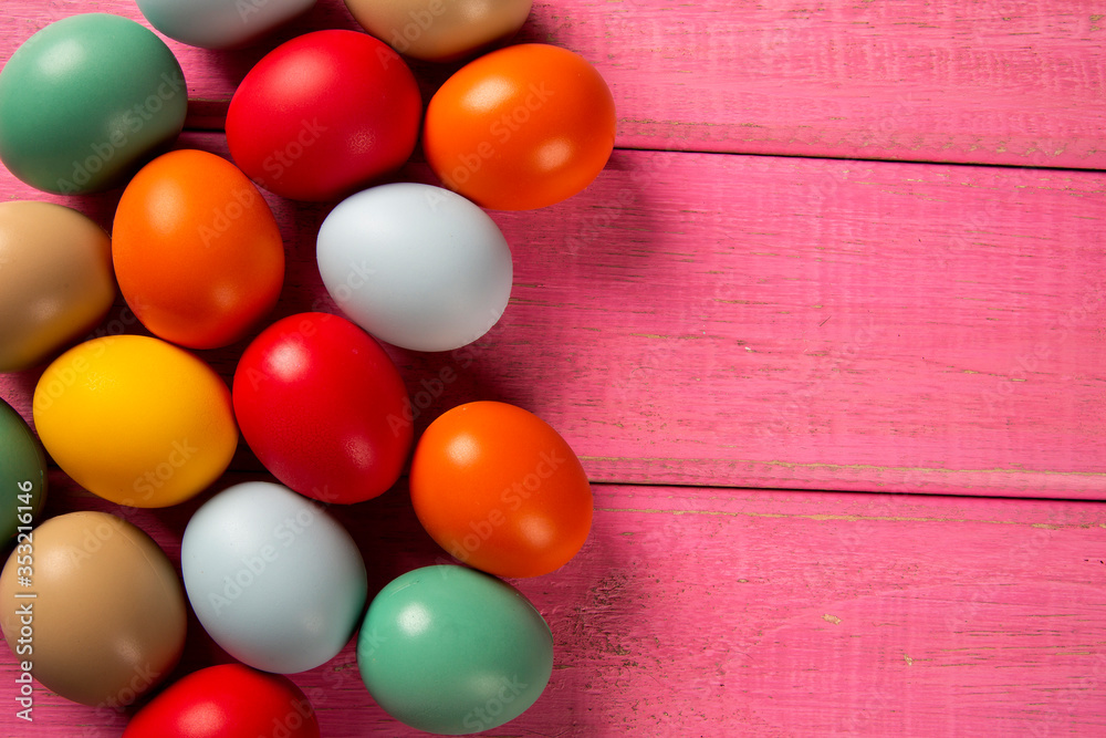 Top view of multicolored Easter eggs on rose background.