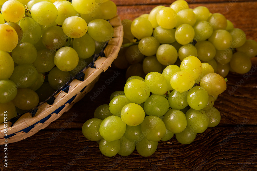Bunch of green grapes in the basket, fruits of autumn, a symbol of abundance on rustic wood background with copy space, top view, close-up Bunch of green grapes in the basket, fruits of autumn, a symbol of abundance on rustic wood background with copy space, top view, close-up